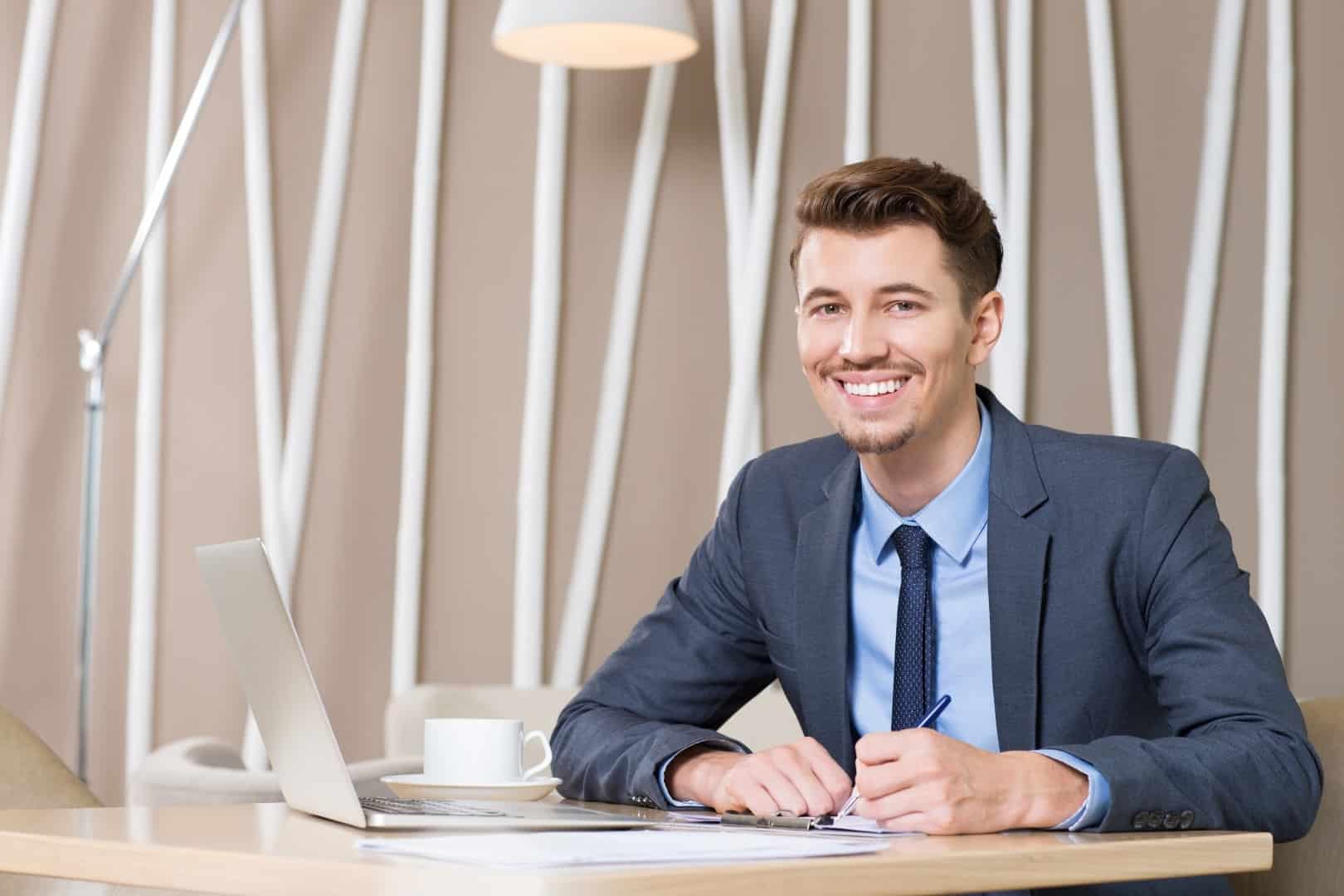 Absolvent des MBA Public Management sitzt im Anzug sitzt in am Arbeitsplatz